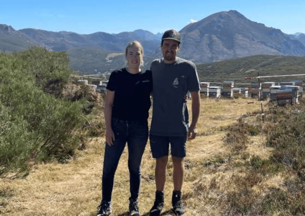 Man and woman standing in front of mountains with hives in the background