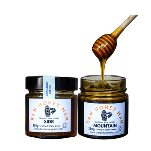 Two jars of Raw Honey Man honey with a honey dipper on a white background