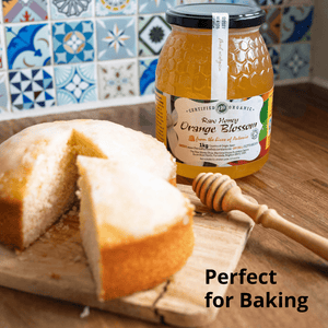 A jar of honey orange blossom jam stands on a wooden surface beside a sliced loaf of bread and a wooden honey dipper, with a tiled kitchen backsplash in the background and the text 'Perfect for Baking' overlaid at the bottom right.