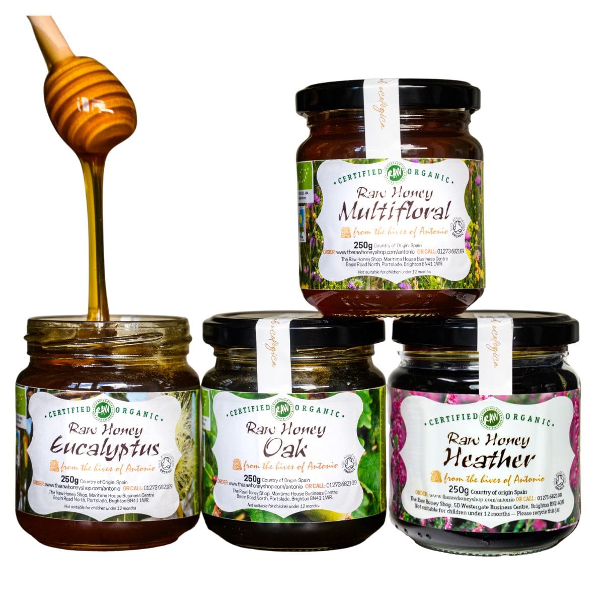 Four jars of Certified Organic Raw Honey from the Inner Lands of Botswana arranged on a white background, with a wooden honey dipper dripping honey into the leftmost jar. The jars are labeled Raw Honey Eucalyptus, Raw Honey Oak, Raw Honey Heather, and Raw Honey Multifloral.