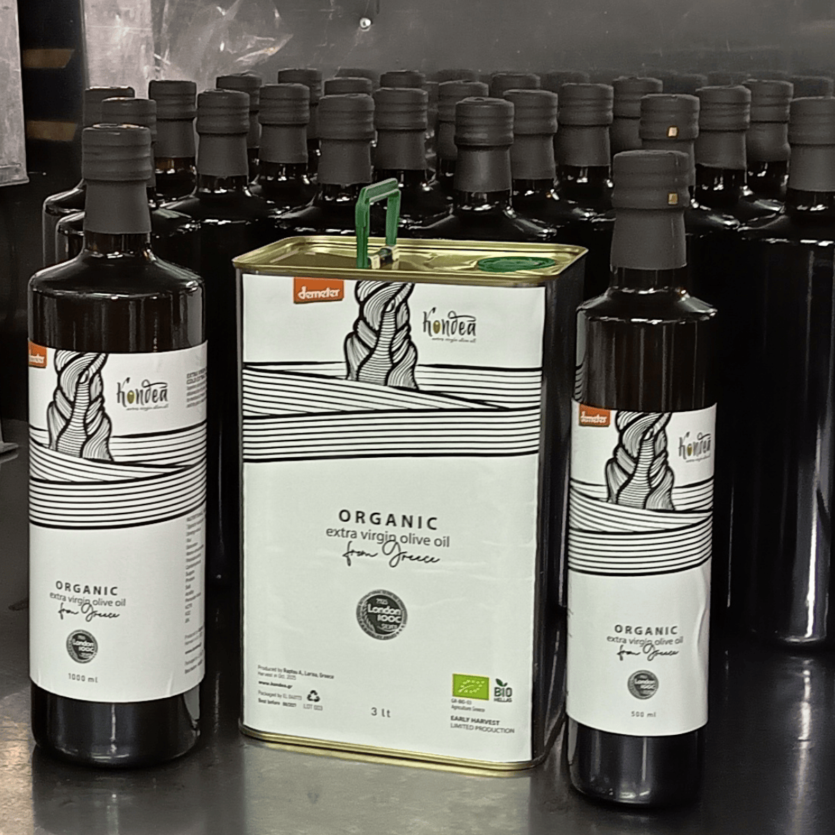 Tin of olive oil with white label surrounded by dark bottles of olive oil