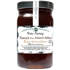 Dark brown honey in a glass jar with white label to front.