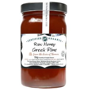 Caramel coloured honey in glass jar with white label to front.