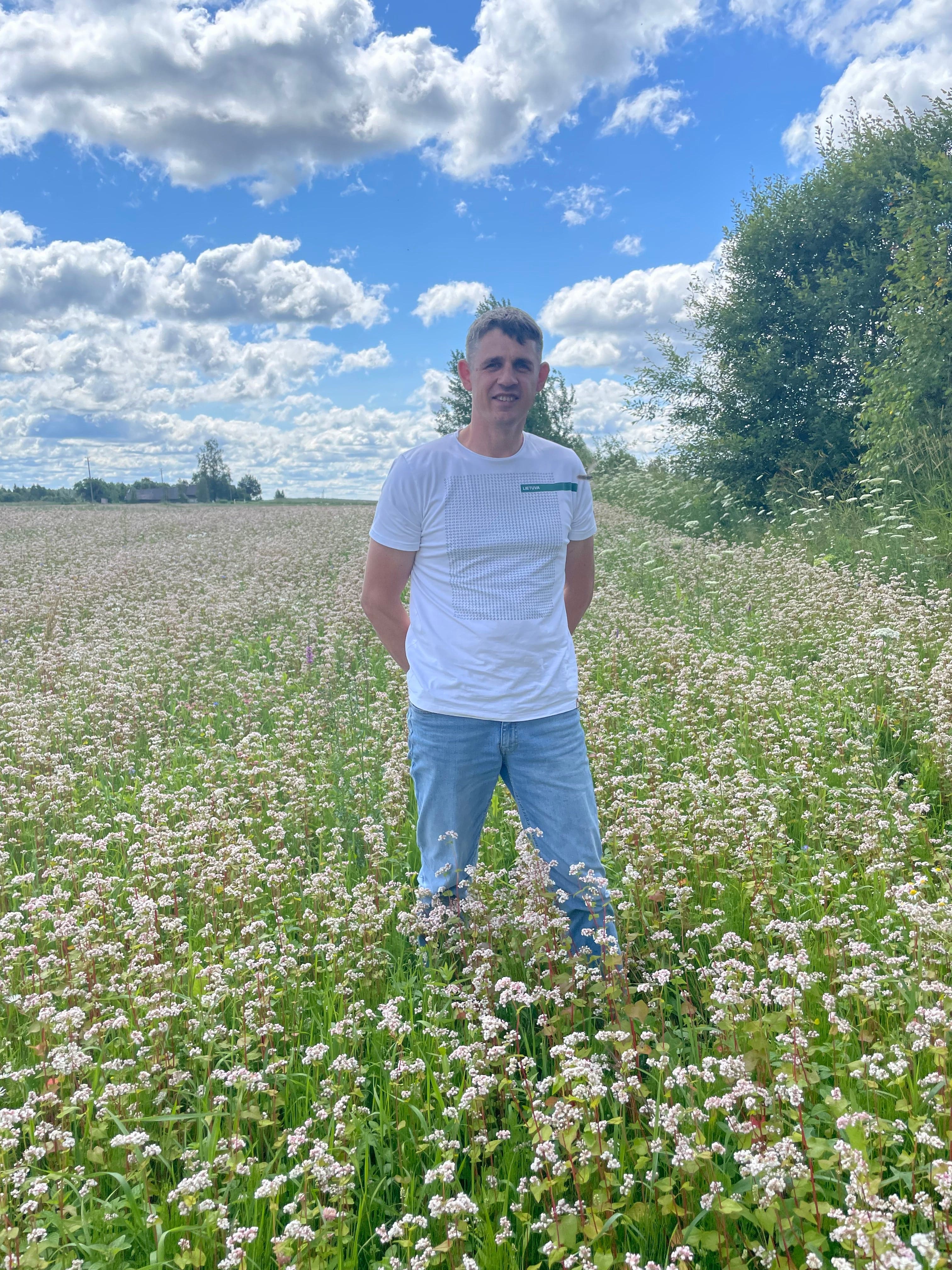 Beekeeper Laimonas standing in a field in Lithuania of flowering Buckwheat.