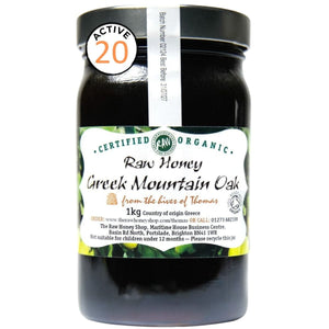 Very dark brown honey in a glass jar with a white label to the front of the jar