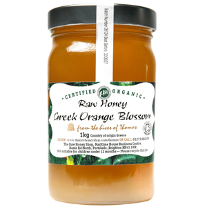 Orange coloured honey in a clear glass jar with white label to front.