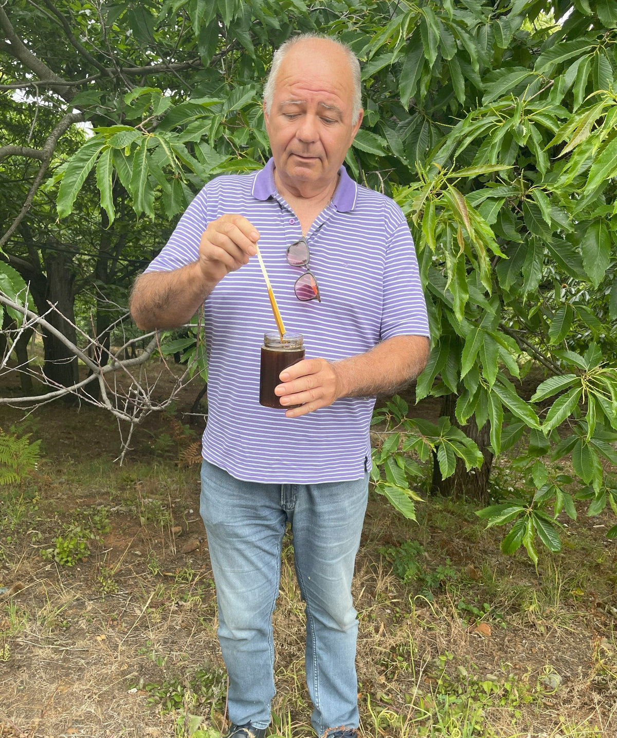 Beekeeper Kostas, holding large jar of raw organic bioactive forest honey.