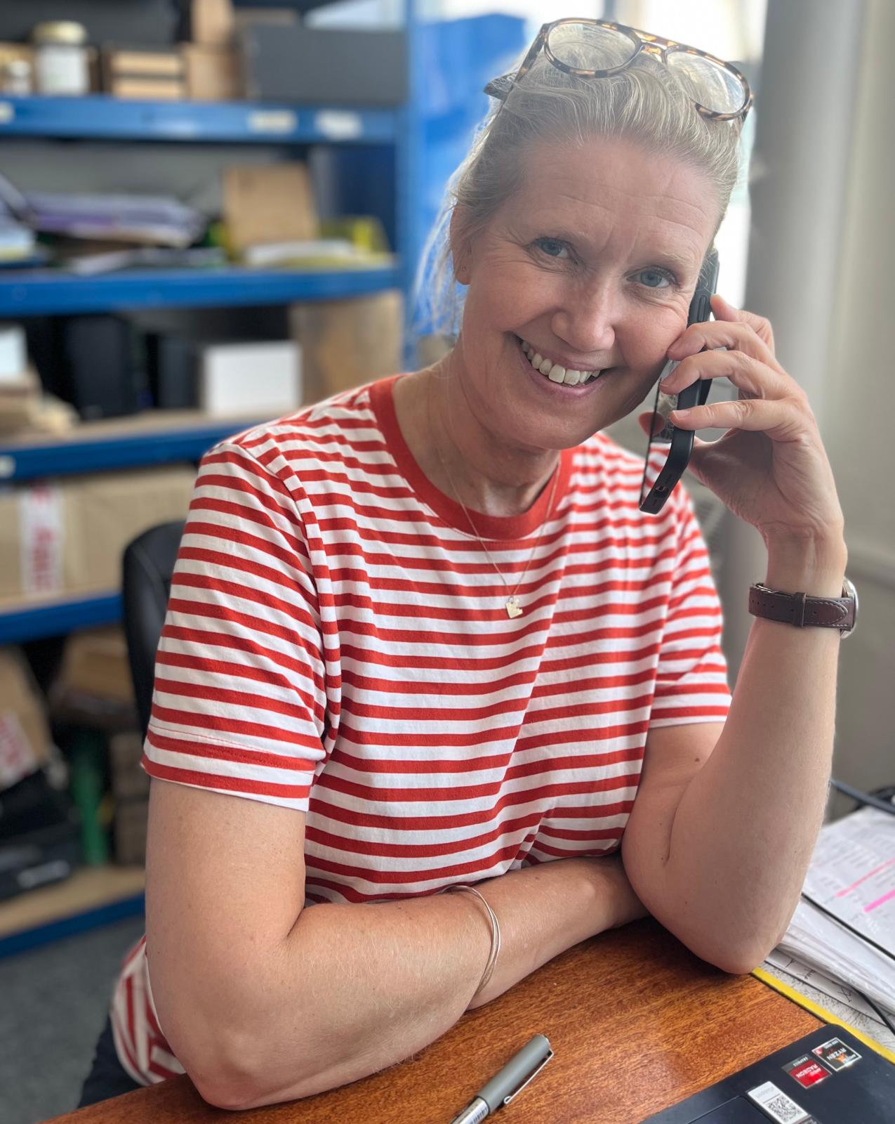 Woman in a striped shirt talking on a phone in an office setting