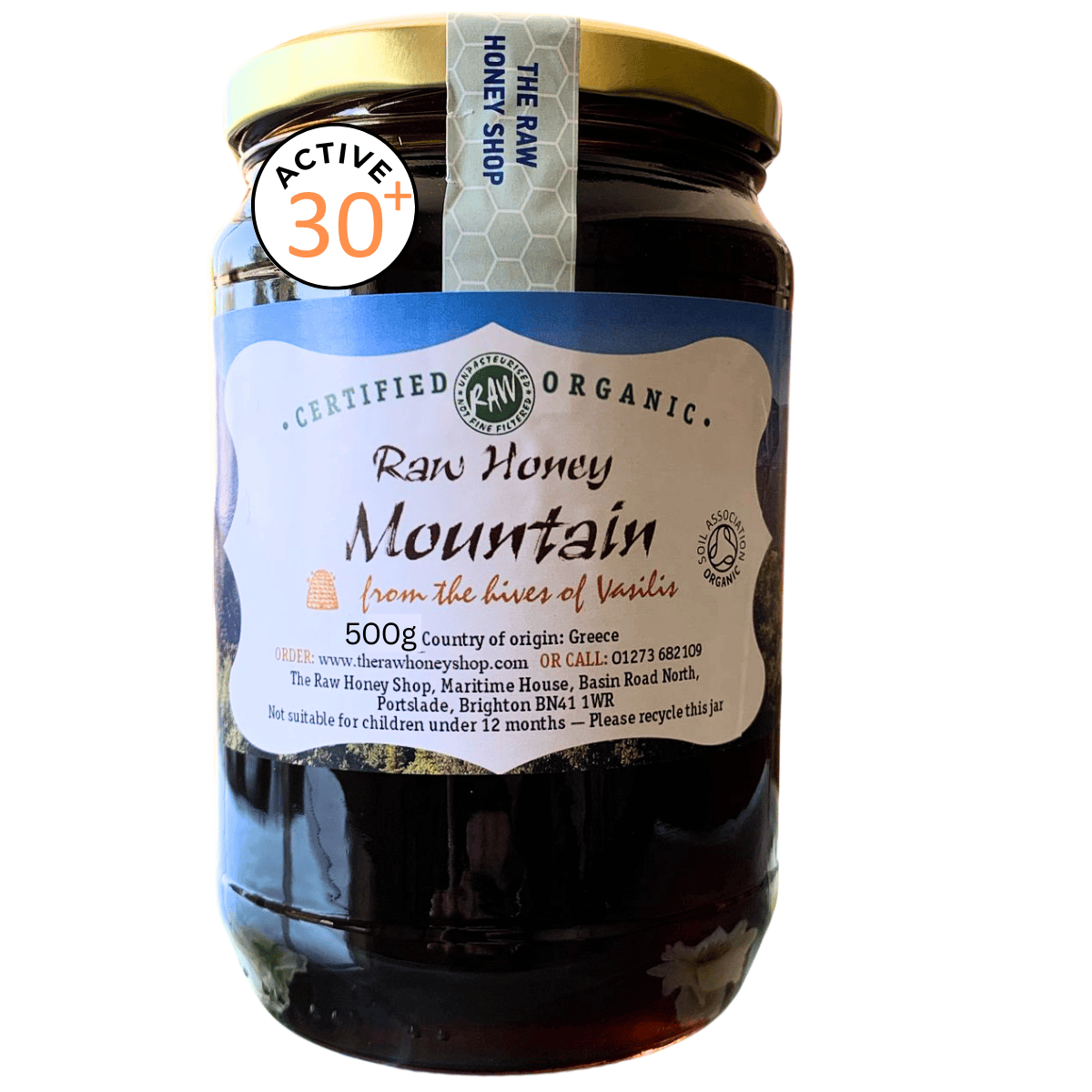 Black honey in a clear glass jar with white label to the front with text Raw Honey Mountain.