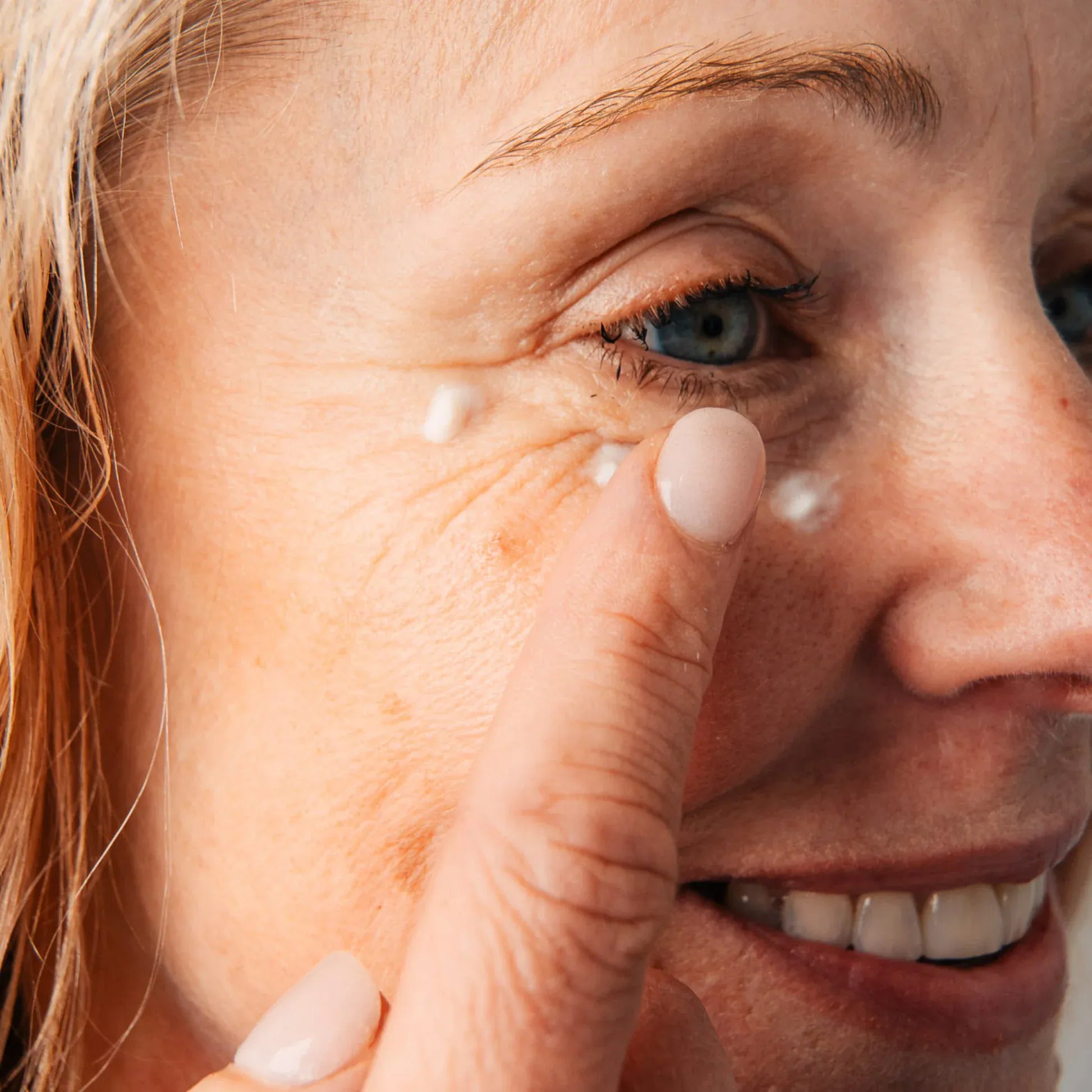 Woman applying cream under her eye with a finger