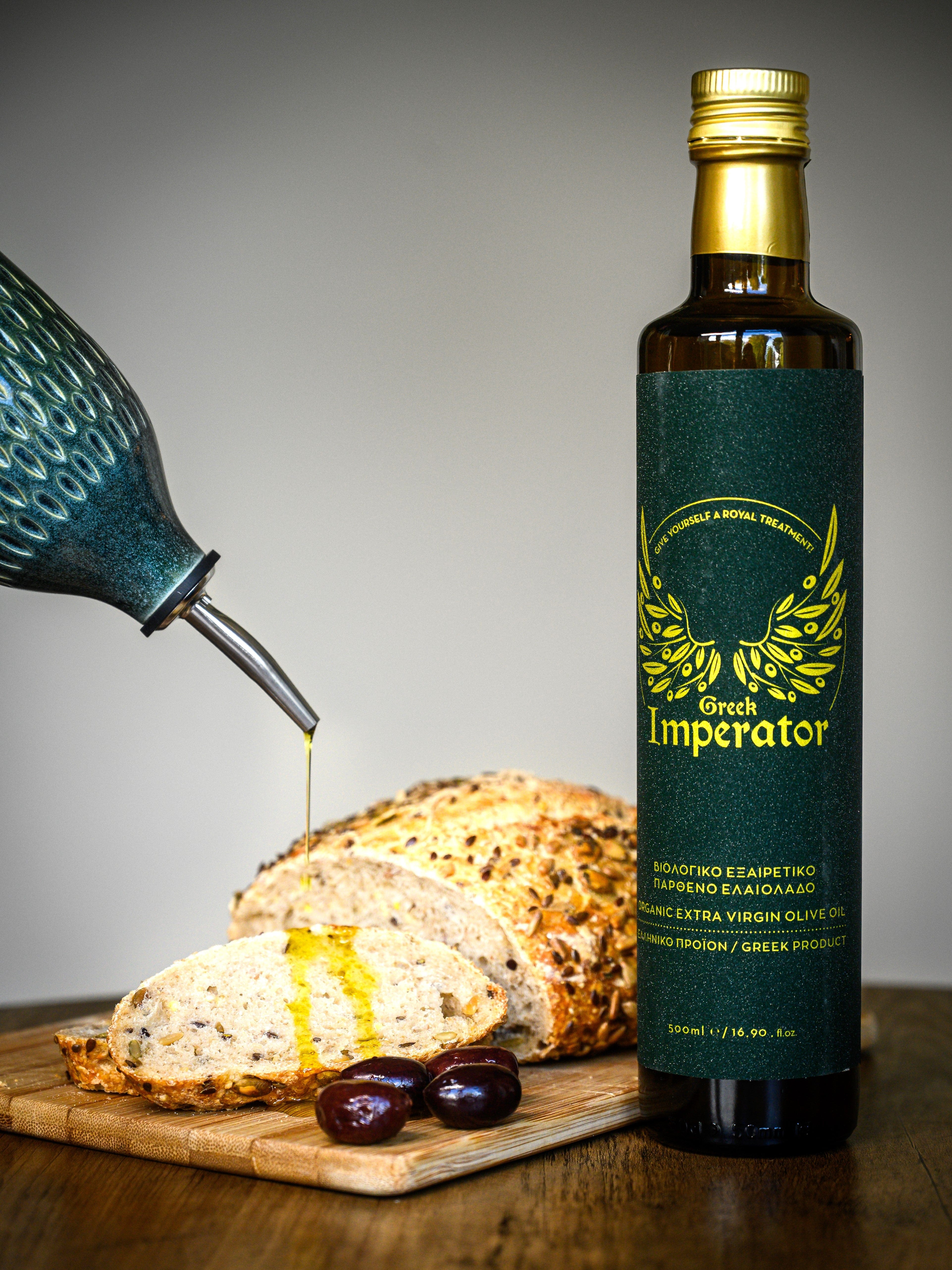 Bottle of Green Imperator olive oil with bread and olives on a wooden board