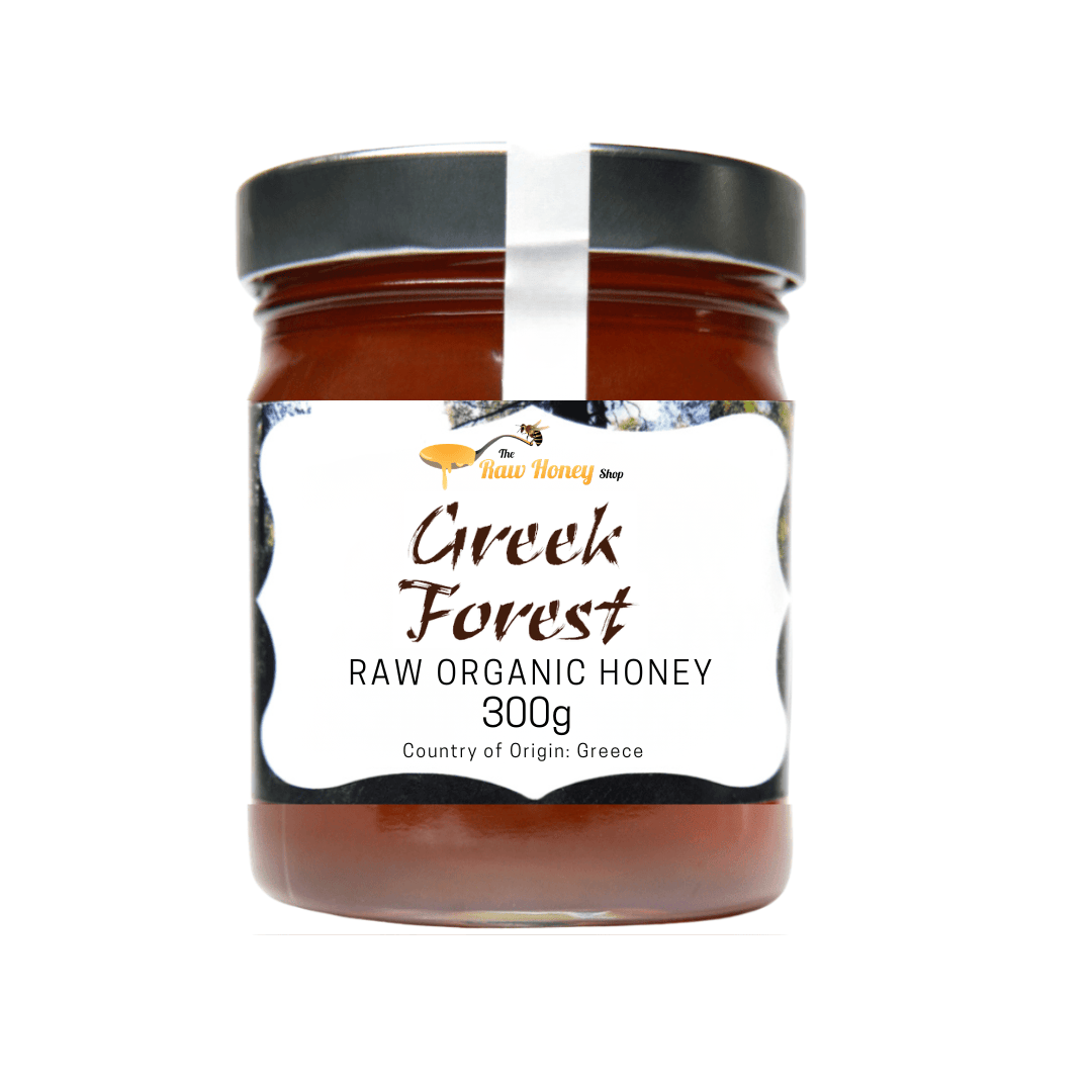 A 300g glass jar of Greek Forest Raw Organic Honey by New Honey Shop, featuring a black lid and a white label with brown text, set against a plain white background.
