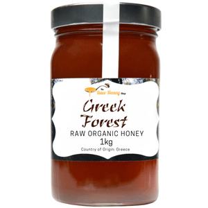 A 1kg glass jar of Greek Forest Raw Organic Honey from The Raw Honey Shop, featuring a black lid and a white label with brown text, set against a plain white background.