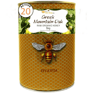 A 5kg can of Thomas' Greek Mountain Oak Raw Organic Honey from The Raw Honey Shop, featuring a golden honeycomb-patterned label with an illustration of a bee and a white label at the top.