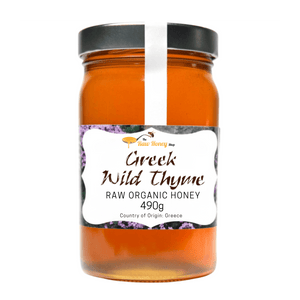 A 490g jar of Thomas' Greek Wild Thyme Raw Organic Honey by The Raw Honey Shop featuring amber-colored honey in a glass jar with a black lid and a white label.