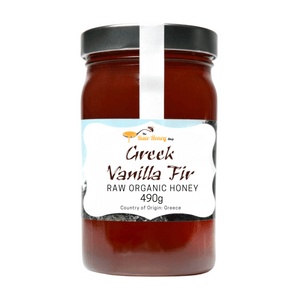 A 490g jar of Greek Vanilla Fir Raw Organic honey from The Raw Honey Shop, featuring a black lid and a white label with brown text, set against a plain white background.