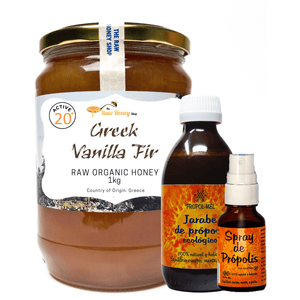 A large glass jar of Greek Vanilla Fir raw organic honey with a gold lid and white label, alongside two smaller amber bottles and a spray bottle from the same brand, all on a plain white background.