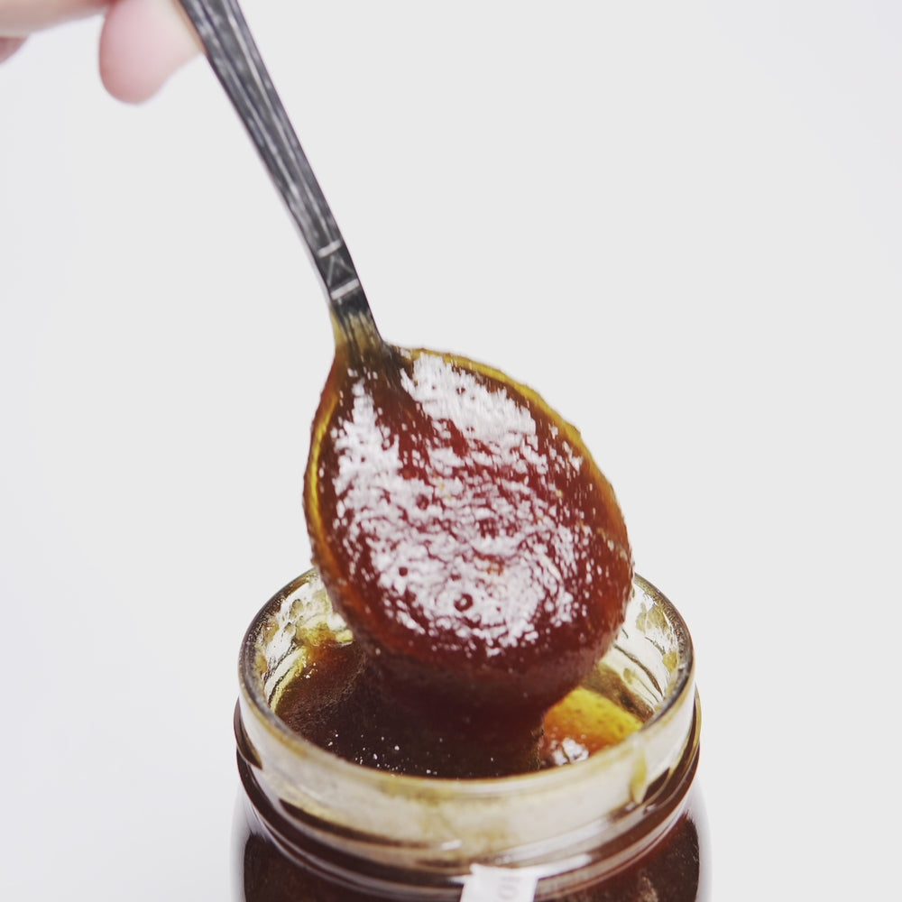 video of metal spoon dripping into an open jar of raw organic Greek mountain oak honey.