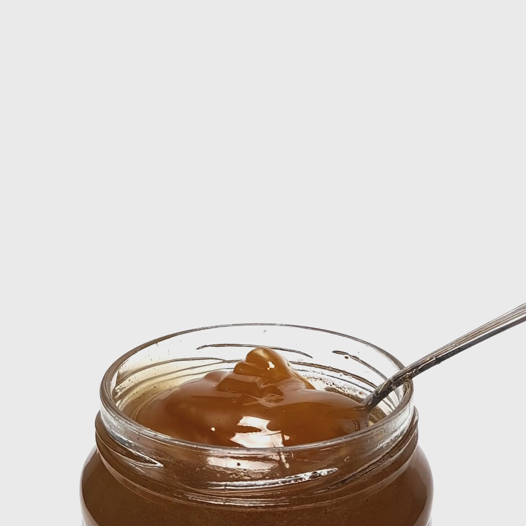 Raw Vanilla Fir Honey pouring from a spoon. 