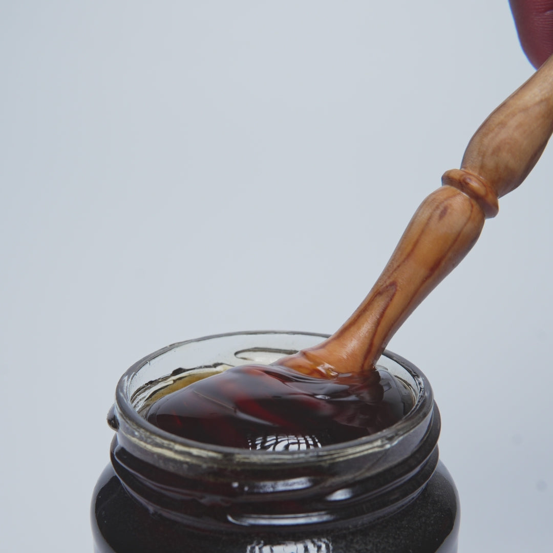 video of wooden honey dipper in open jar of organic chesnut honey 