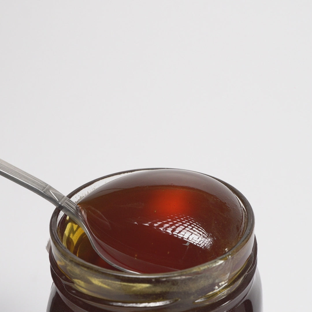 video of metal spoon dripping into an open jar of raw organic Greek red fir honey.