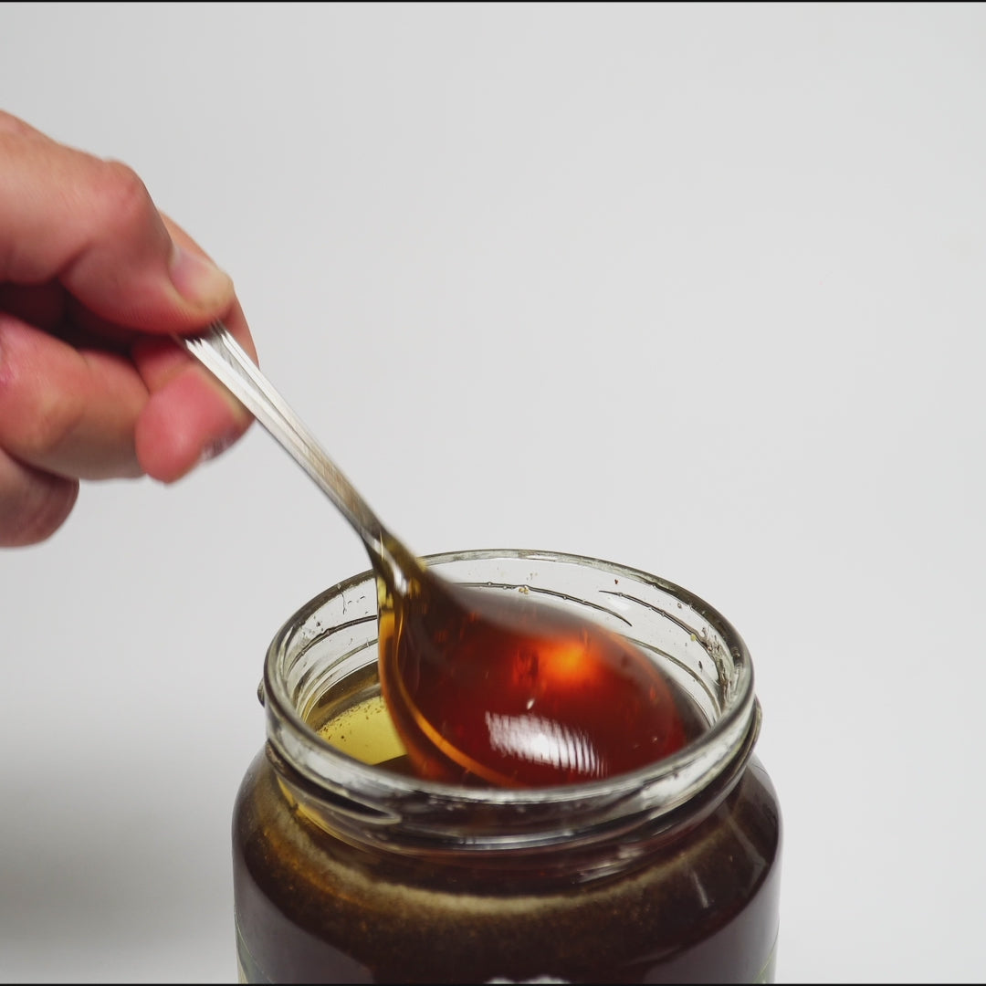 video of metal spoon dripping into an open jar of raw organic Greek sidr honey.