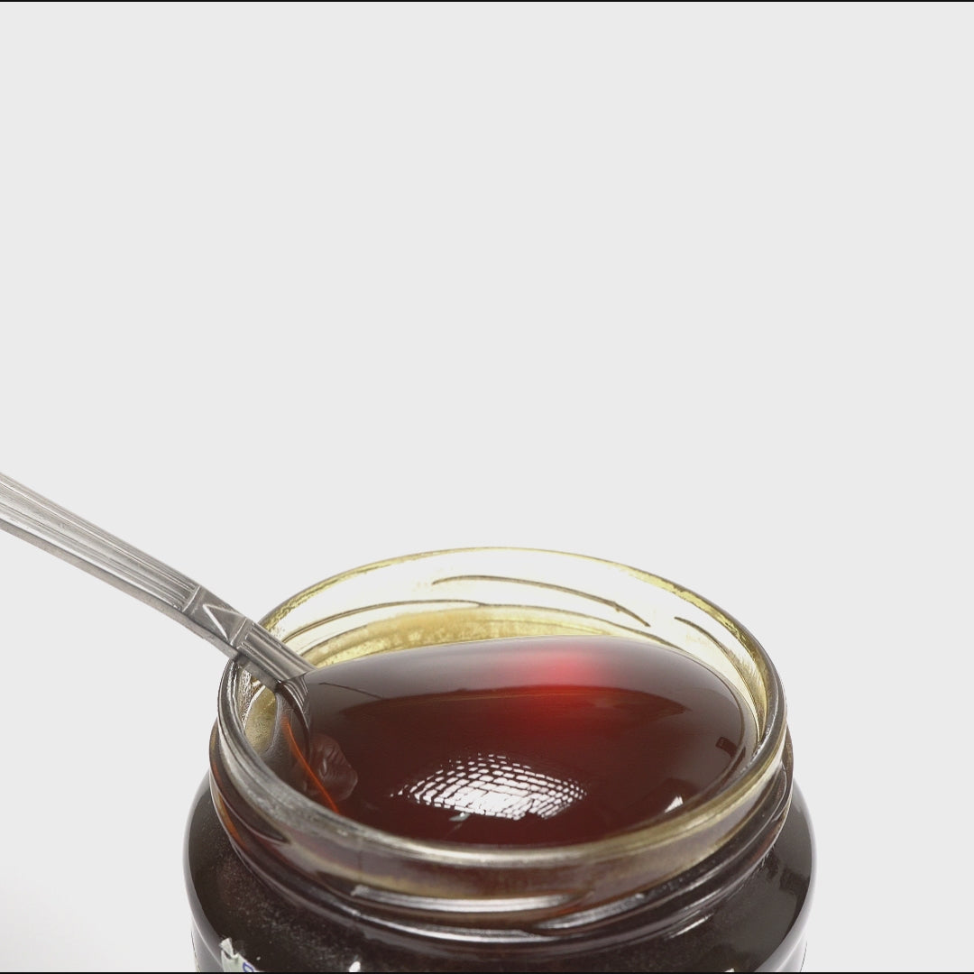 video of metal spoon pouring honey into an open jar of raw organic bioactive forest honey.