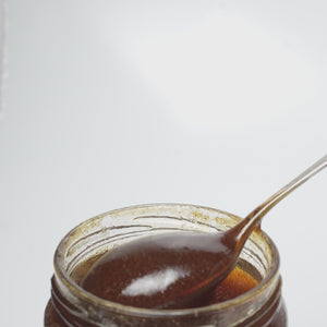 video of wooden honey dipper  dripping into an open jar of raw organic bell heather and mountain calluna honey