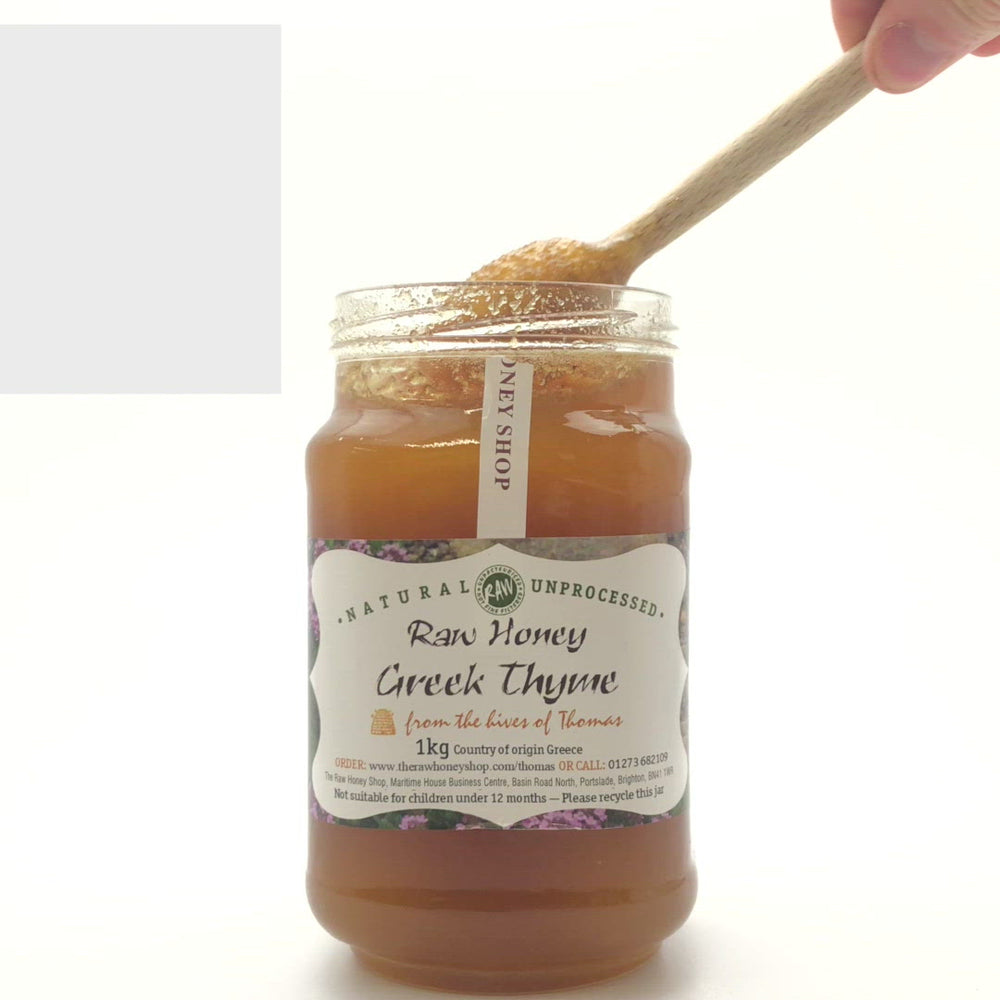 video of wooden honey dipper  dripping into an open jar of organic Greek thyme honey
