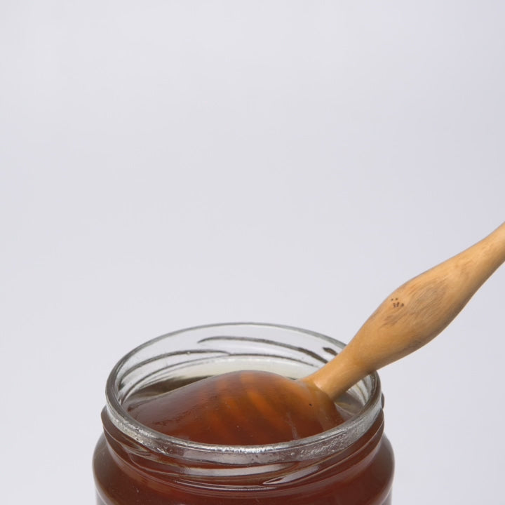 video of wooden honey dipper in open jar of organic eucalyptus honey