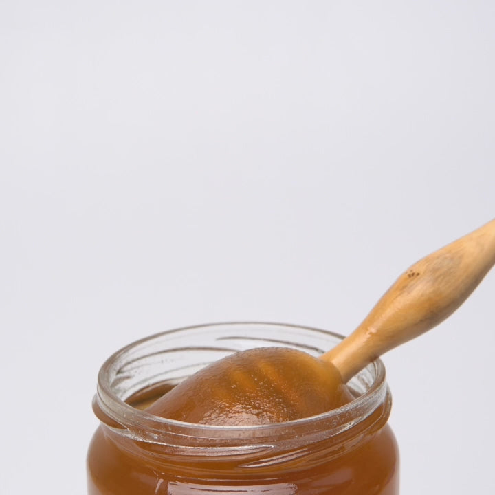 video of wooden honey dipper  dripping into an open jar of organic lavender honey